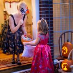 Costumed homeowner offers candy to child trick-or-treater