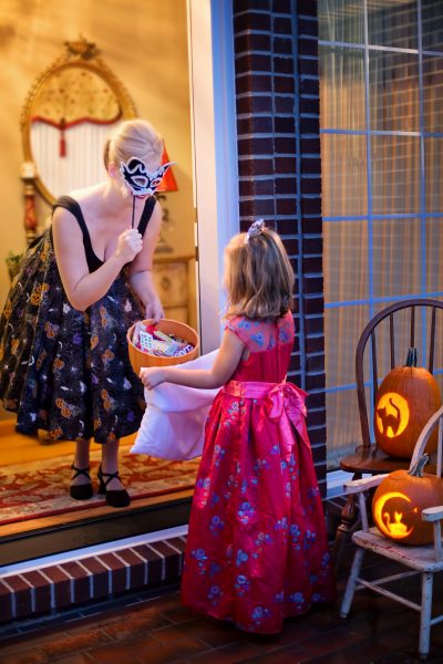 Costumed homeowner offers candy to child trick-or-treater