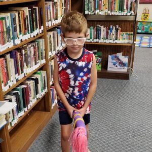 a child poses with a stick horse in the library